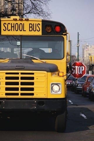 Yellow school bus with its stop sign extended, signaling the upcoming transition back to the school routine.