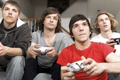 Four teenage boys focused intently on video games, illustrating the challenge of getting children to follow instructions.