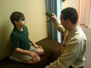 Dr. Mane holds a small model airplane to guide a young patient wearing tinted glasses during a Hemispheric Integration sessio