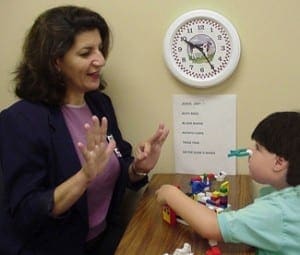 Speech therapist using hand gestures to instruct a young boy wearing a nose clip while playing with blocks during P.i.N.C.H.