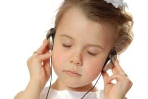 Young girl with closed eyes listening intently to music through headphones as part of her sensory therapy plan.