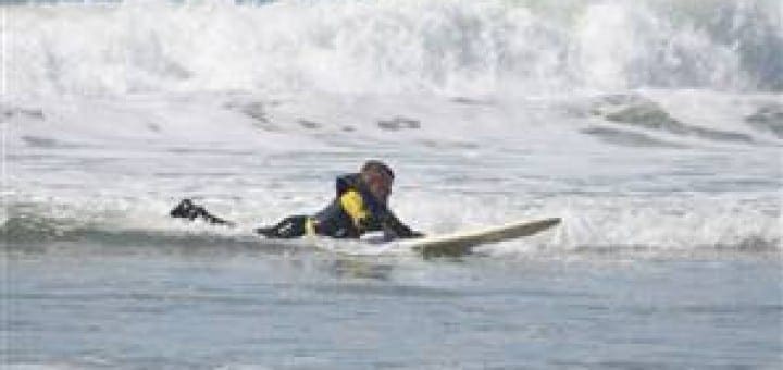 Fourteen-year-old Patrick Ivison paddling on a surfboard in the ocean waves.