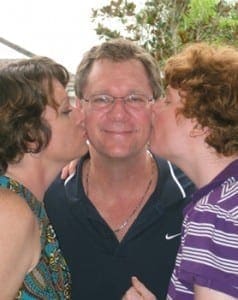 Two women kiss a man on the cheeks.