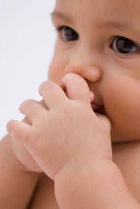 Baby's hands are near their mouth.