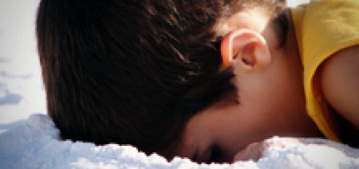 Boy with head down in the sand, focusing on the details.