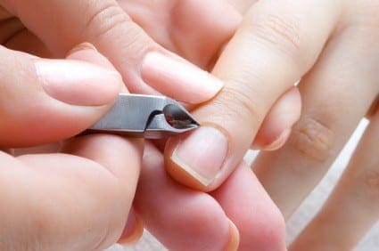 Hands trim nails with cuticle nippers.