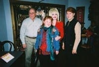 Patricia stands smiling between her parents and Dolly Parton in celebration of her high school graduation.