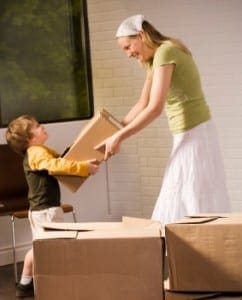 Mother hands a box to her son while packing for a move.