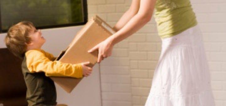 Mother hands a box to her son while packing for a move.