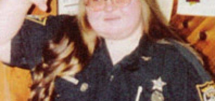 Terry wearing a police uniform and sheriff-style hat while performing a salute to honor her lifelong dream.