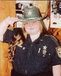 Terry wearing a police uniform and sheriff-style hat while performing a salute to honor her lifelong dream.