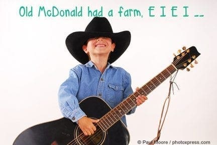 A smiling child in a cowboy hat plays an acoustic guitar, with "Old McDonald had a farm, E I E I ___" superimposed.