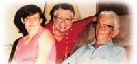 Jane, her sister, and their father sitting together and smiling.
