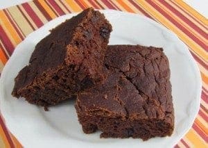 Two slices of rich chocolate gingerbread sit on a white plate.