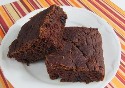 Two slices of rich chocolate gingerbread sit on a white plate.