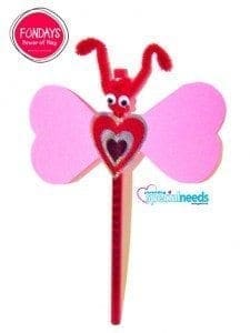 Crafted dragonfly or butterfly with pink heart wings and a red heart body on a stick.