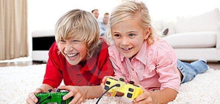 Two children excitedly play a video game with controllers.