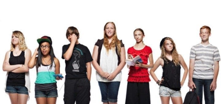 Seven young students stand in a line against a white background.