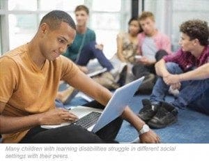 A group of diverse teenagers study together on the floor, with one boy in the foreground typing on a laptop.