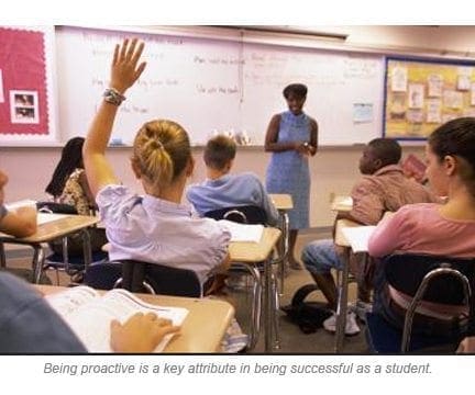 Teacher in a classroom with a student raising her hand.