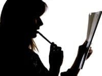 Silhouette of a woman reading a book intently.