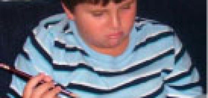 Evan holds a pencil while looking frustrated as he reads a book.