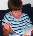 Evan holds a pencil while looking frustrated as he reads a book.