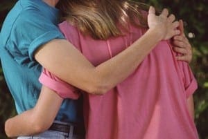 Parent and child embrace in a supportive hug, reflecting the emotional transition of puberty.