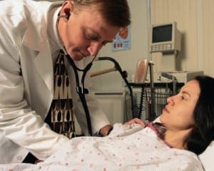 Doctor using a stethoscope to examine a patient in a medical office to promote personal health responsibility.