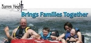 Family riding on an inflatable tube in the water.
