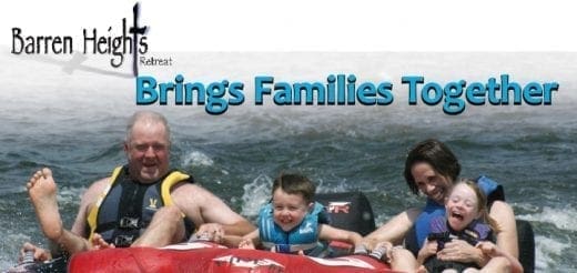 Family riding on an inflatable tube in the water.