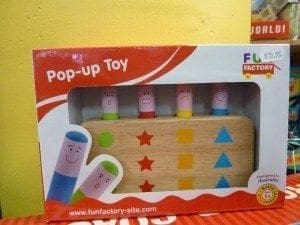 Pop-up toy in its original packaging with wooden pegs and colorful shapes.