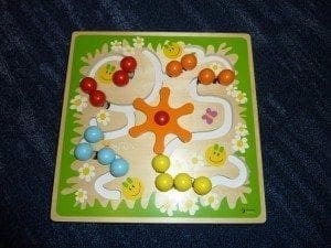 Wooden bead maze toy with colorful beads and smiling suns on a green background.