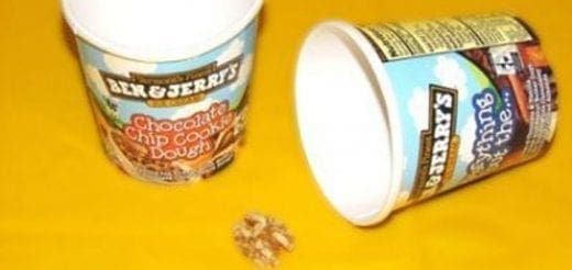 Two Ben & Jerry's ice cream cups and a walnut on a yellow surface.
