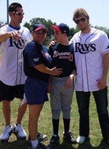 The author's mother, Linda Cage, hugs her son Nicholas while two other men in baseball uniforms look on.