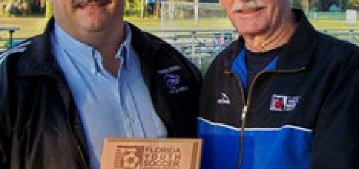 Dean Frost and another man hold a plaque from the Florida Youth Soccer Association.