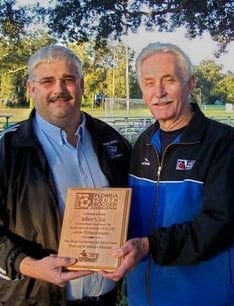 Dean Frost and another man hold a plaque from the Florida Youth Soccer Association.