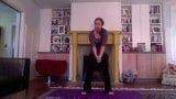 A woman in workout clothes leads a yoga class from her living room.