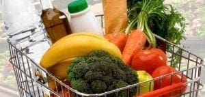 Shopping cart filled with fresh produce, bread, and bottled drinks.