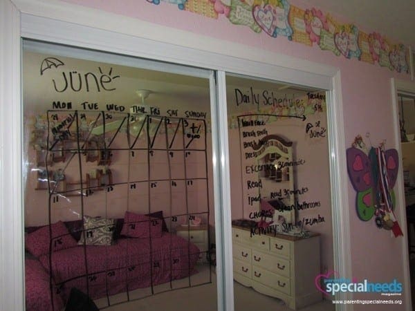 Closet mirror doors with a June calendar and daily schedule written in dry erase marker.