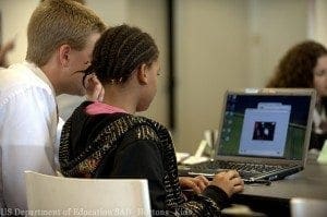 Adult assists a student using a laptop for digital storytelling.