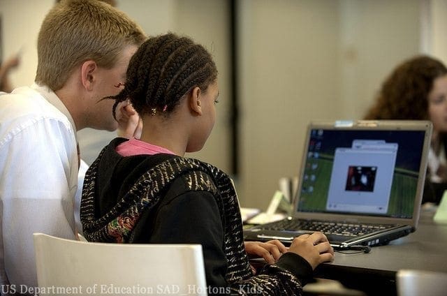 Adult assists a student using a laptop for digital storytelling.