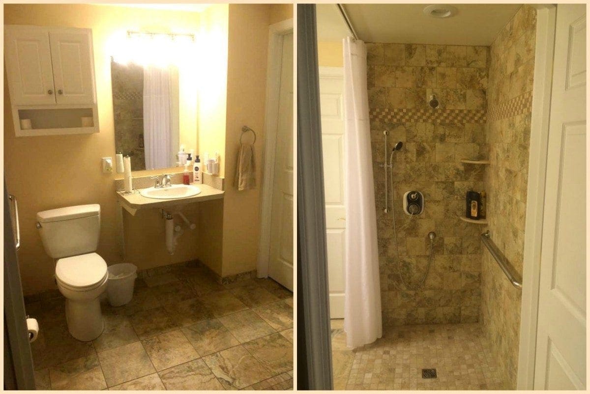 Accessible bathroom with a roll-under sink, toilet, and a walk-in shower with multiple shower heads and grab bars.
