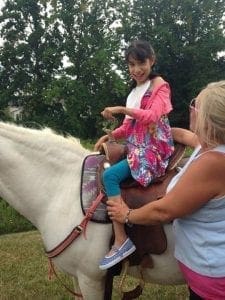 Nubia Smith on a white horse with a woman assisting.