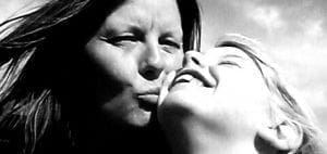 Two people share a kiss outdoors.