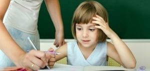 A teacher helps a young student with her schoolwork.