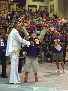 Special Olympian receives a letter jacket from an Elvis impersonator at a pep rally.