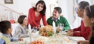 A family is gathered around a table for a holiday meal with a roasted turkey.