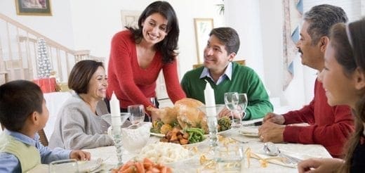 A family is gathered around a table for a holiday meal with a roasted turkey.