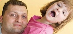 Man holding a distressed child with mouth open.